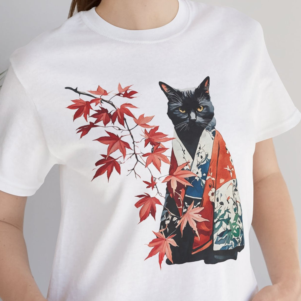 Person wearing a white t-shirt with a black cat and red leaves design, standing indoors.