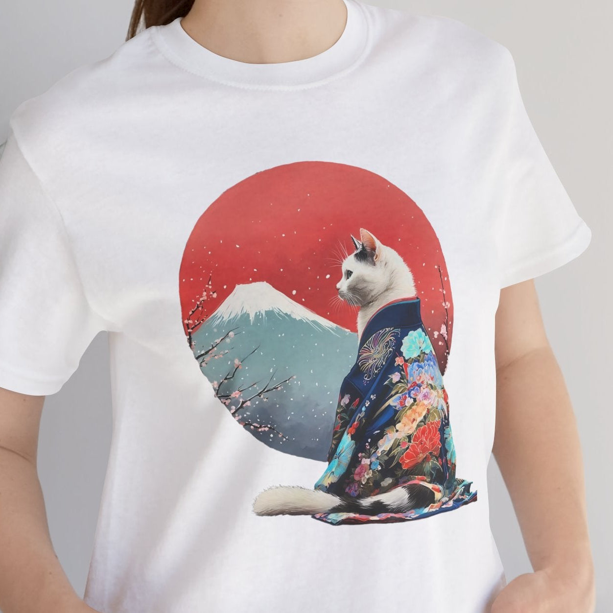 Person wearing a white t-shirt with a cat in a kimono design against a red sun and mountain background.