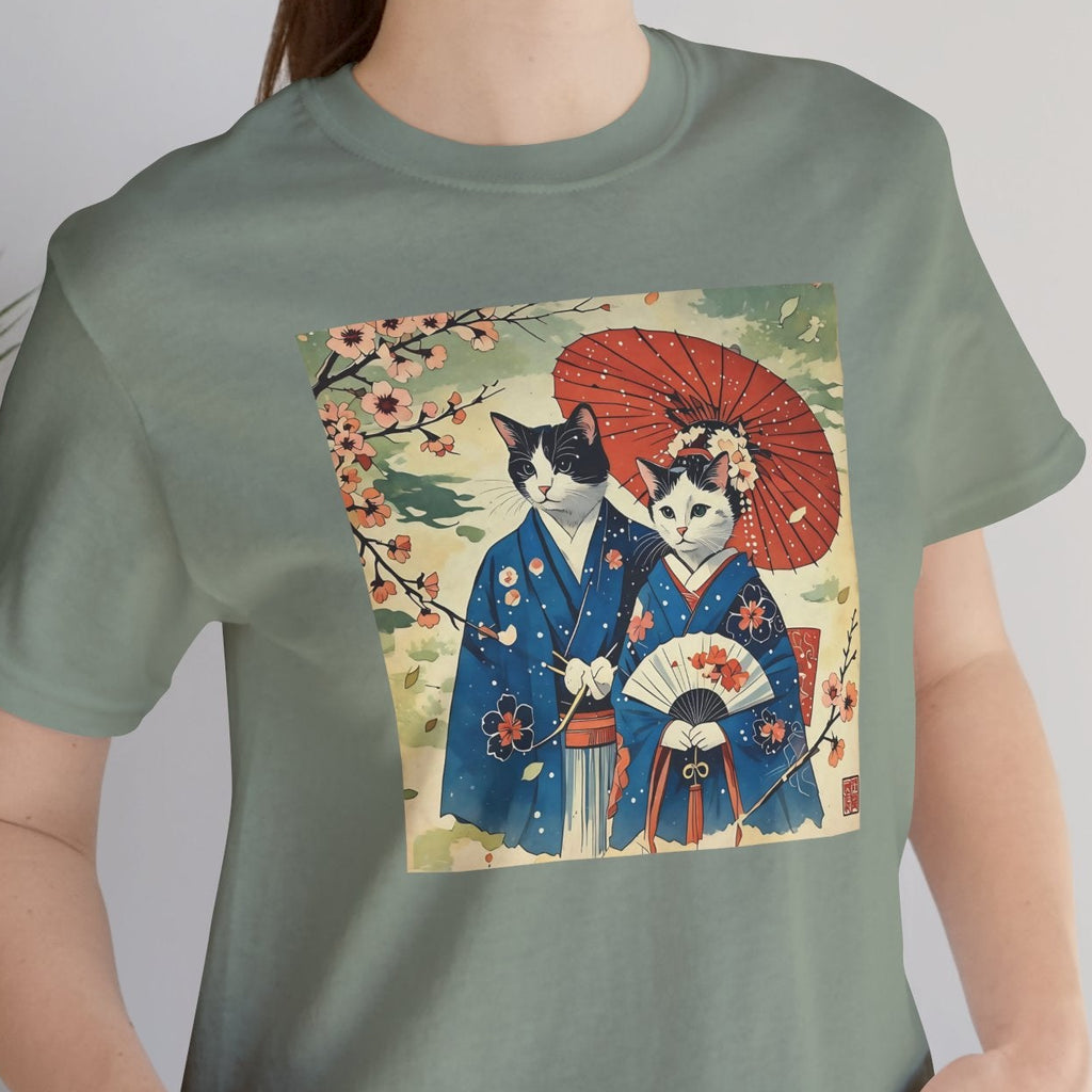 Person wearing a green t-shirt with a graphic of two cats in traditional Japanese clothing.