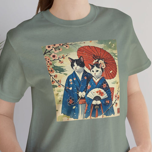 Person wearing a green t-shirt with a graphic of two cats in traditional Japanese clothing.