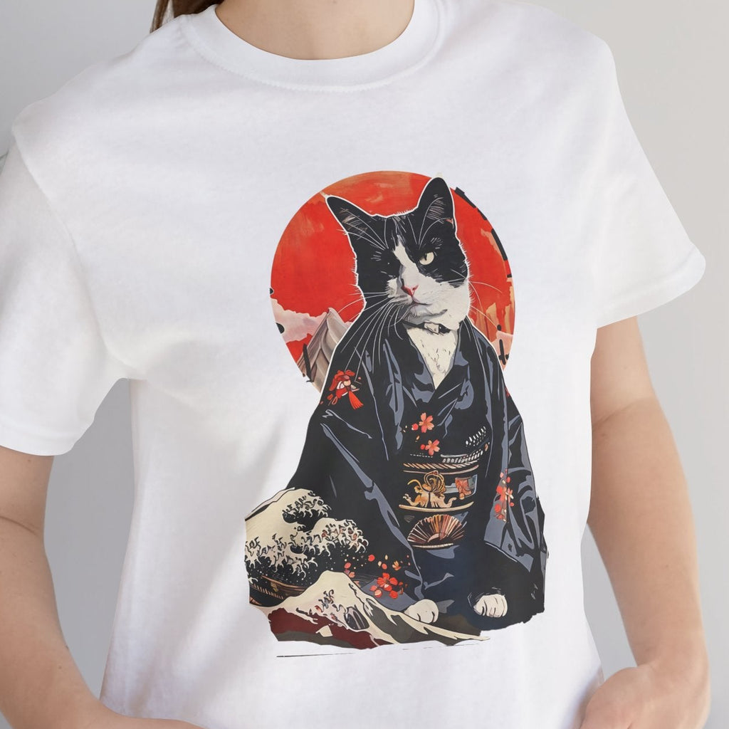 Person wearing a white t-shirt with a cat in a kimono design, standing indoors next to a plant.