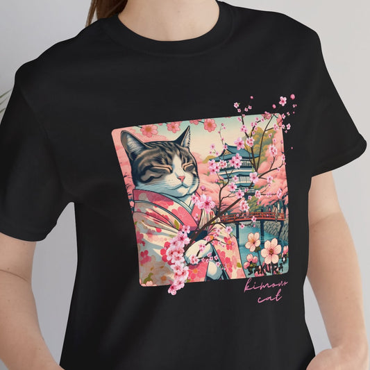 Person wearing a black t-shirt with a cat graphic design, standing indoors next to a plant.